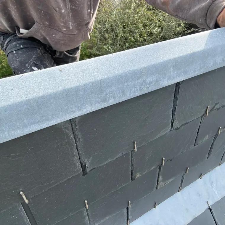 Pose d’une faîtière en zinc sur des ardoises